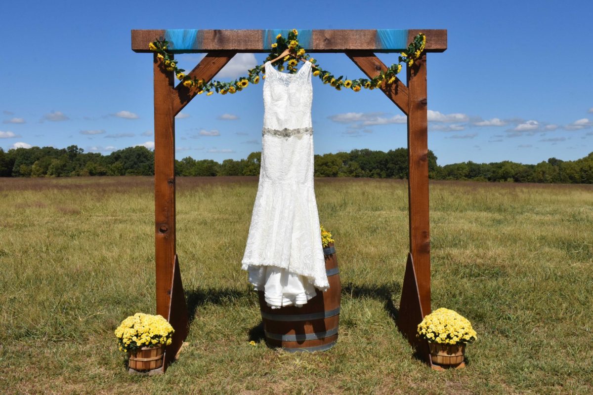 Wedding dress hanging from arbor